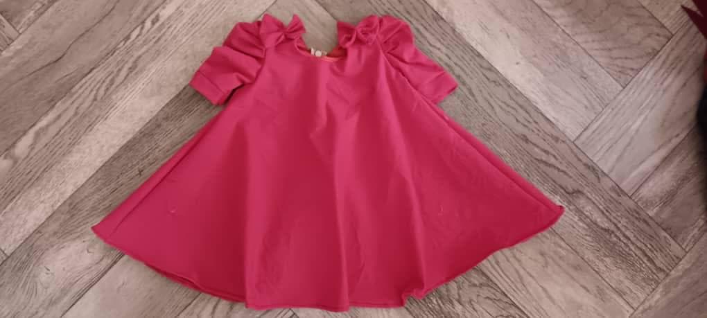 A pink child’s dress with bows